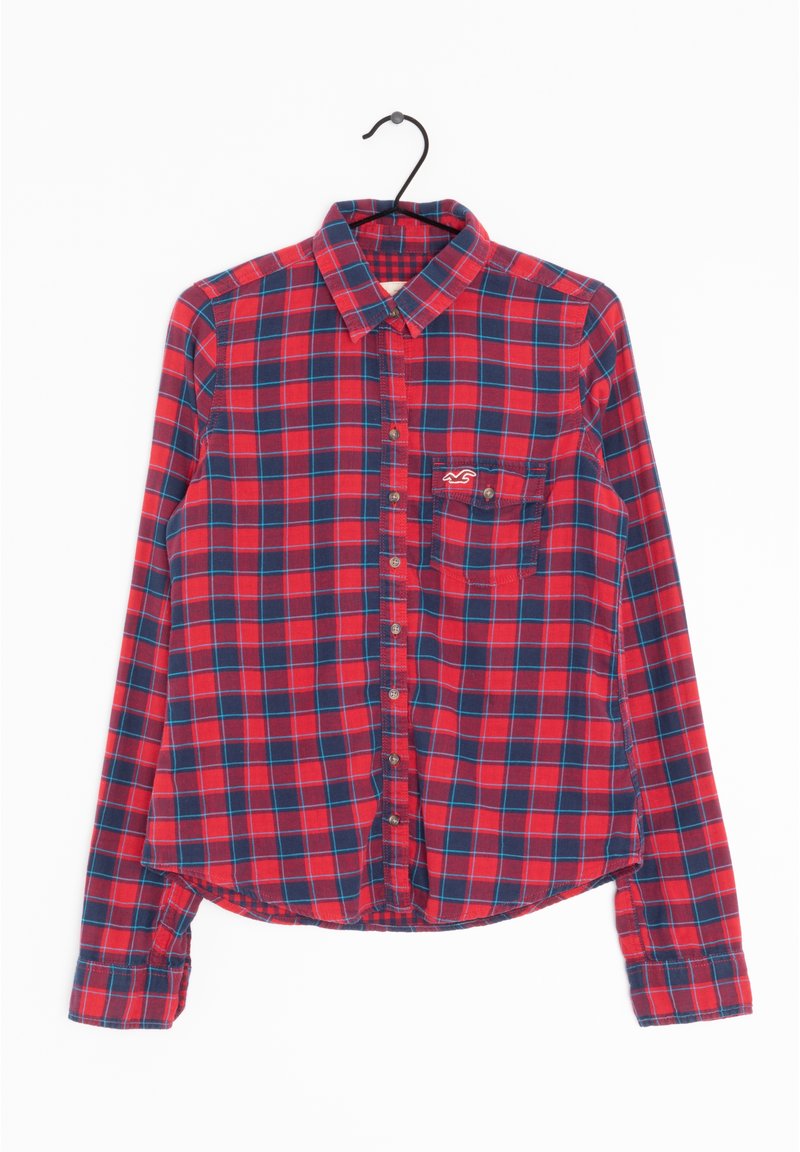 Camicia a maniche lunghe a quadri rossi e blu navy con colletto, chiusura con bottoni e taschino sul petto con un piccolo logo. Tessuto di cotone, leggermente testurizzato.