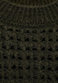 Gestructureerde donker groene gebreide stof met een verhoogd patroon en een ribbelkraag, gemaakt van zacht, pluizig materiaal voor warmte en comfort.