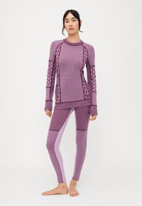 Conjunto de ropa deportiva de color púrpura con estampados que incluye una camiseta de manga larga con texturas variadas y leggings con rayas y estampados en contraste.