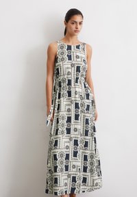 Maxi-jurk met een ronde halslijn, voorzien van een geometrisch zwart, wit en goudpatroon. Gemaakt van lichte stof, met een tailleband detail.
