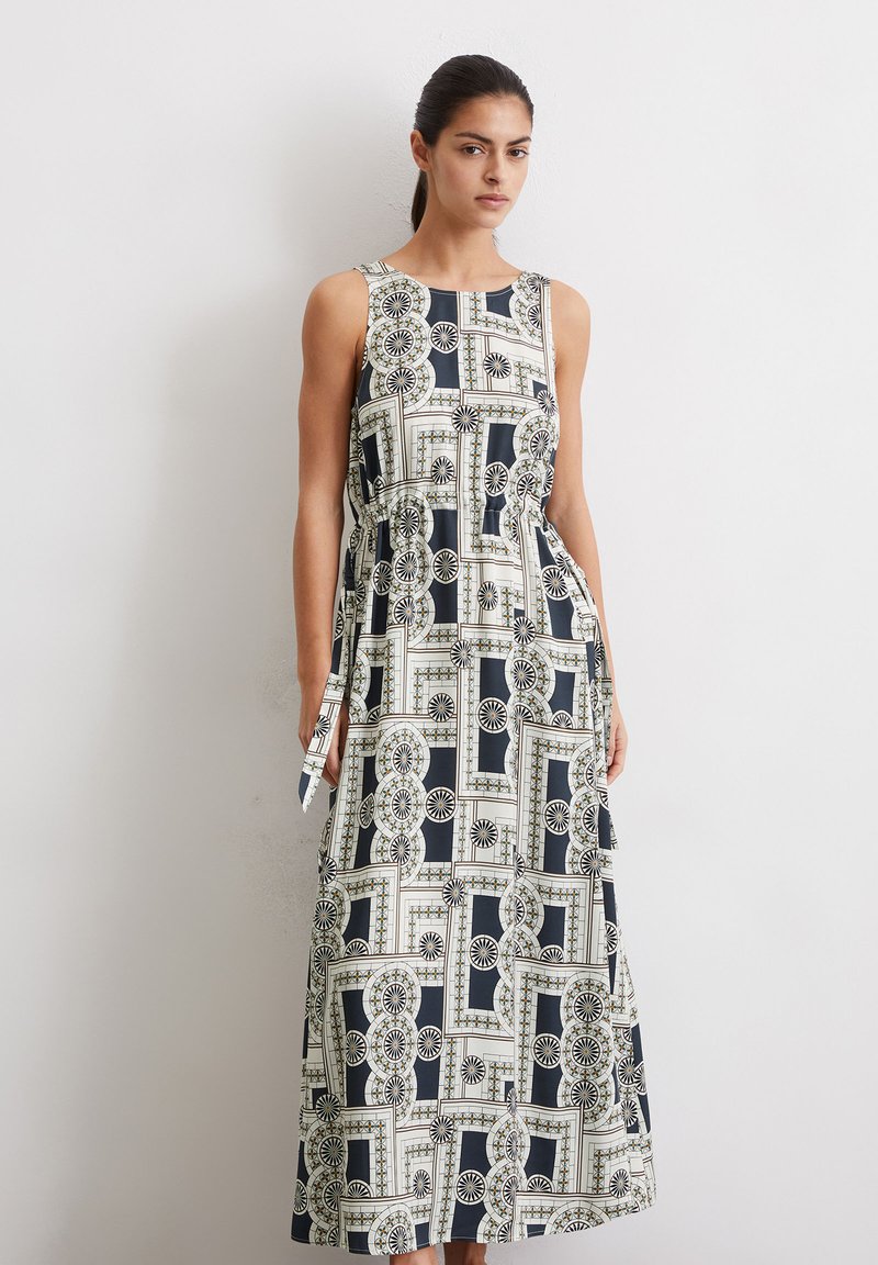 Maxi-jurk met een ronde halslijn, voorzien van een geometrisch zwart, wit en goudpatroon. Gemaakt van lichte stof, met een tailleband detail.