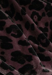 Minkštas aksominis audinys su tamsiai purpuriniu pagrindu ir juodomis nereguliariomis leopardinėmis raštais.