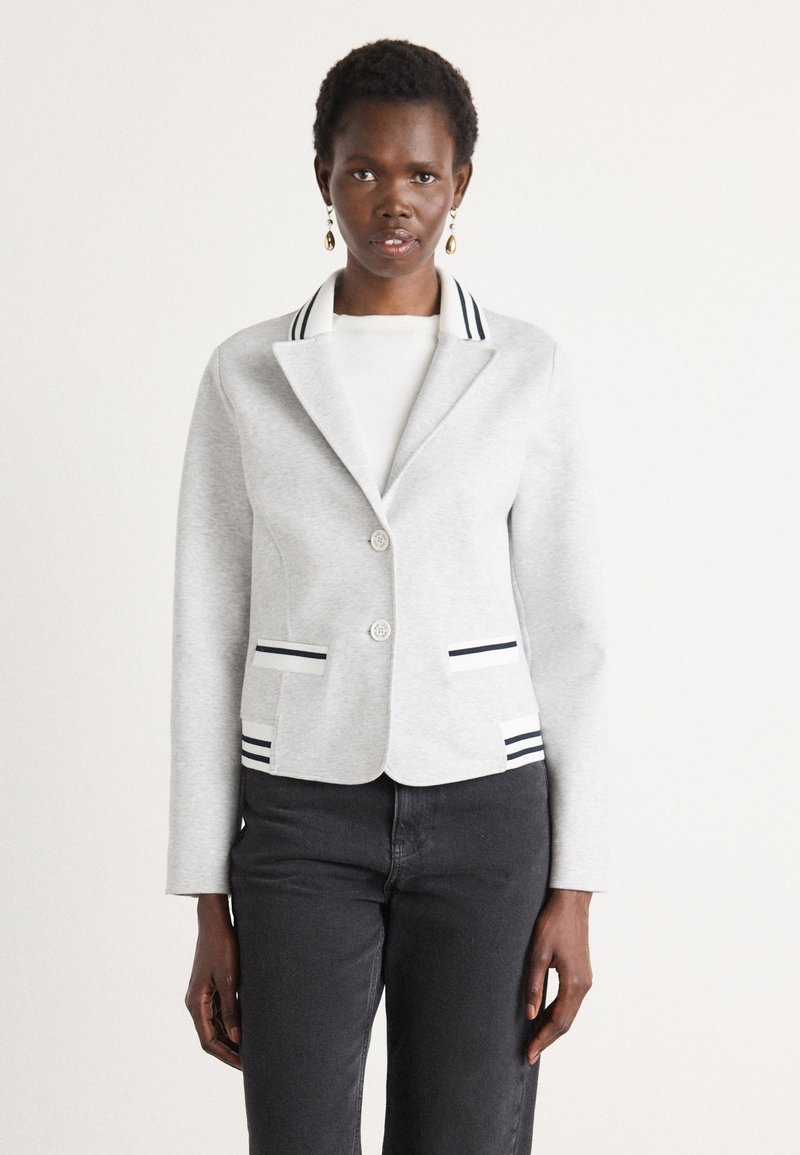 Gray blazer in soft fabric with a notched collar, two buttons, and striped accents on collar and pockets. Paired with black pants.