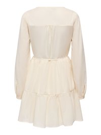 Robe à manches longues couleur crème, à volants, avec une taille froncée et un pli dans le dos, tombant au-dessus du genou.