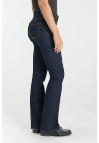 Donkerblauwe uitlopende jeans van denim, met een hoge taille, oranje stiksels en achterzakken met een opvallend embleem.