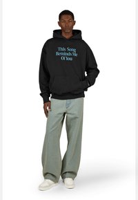 Čierna mikina s modrým textom "Táto pieseň mi pripomína teba." Obsahuje klokanie vrecko a rebrované manžety. Nosená s svetlo modrými širokými džínsami a bielymi teniskami.