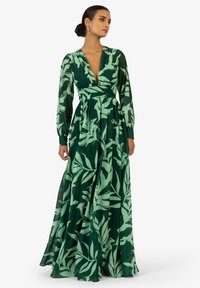 Robe longue verte en tissu léger, avec un décolleté en V profond, des manches longues et un motif de feuilles dans des nuances de vert variées.