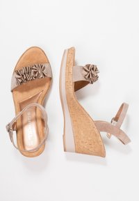 Sandalias de cuña beige con una suela de corcho texturizada, que cuentan con acentos de tela arrugada en la correa y hebilla ajustable en el tobillo.