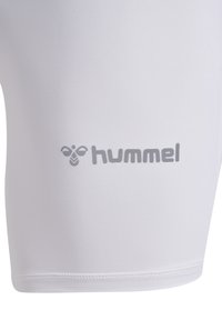 Witte sportieve shorts gemaakt van gladde, rekbare stof. Heeft een grijs "hummel" logo aan de zijkant en platte stiksels langs de zoom.