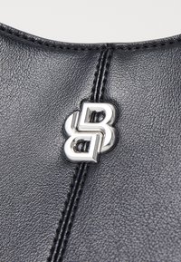 Pelle nera testurizzata con hardware metallico argento prominente caratterizzato da un design di lettere "B" intrecciate, accentuato da linee di cucitura ordinate.
