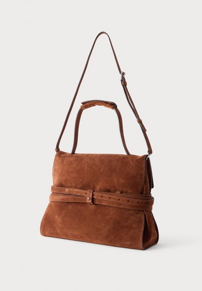 Sac à bandoulière en daim marron avec une sangle réglable, des poignées supérieures et un détail de ceinture assorti enroulé à l'avant.