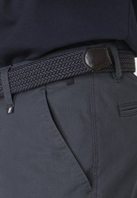 Woven navy belt with leather accents, paired with grey textured pants featuring side pockets and subtle stitching details.