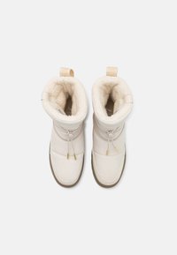 Białe, ocieplane zimowe botki z gładkim wykończeniem, regulowanym sznurkiem i zaokrągloną gumową podeszwą z fakturowanym wykończeniem.