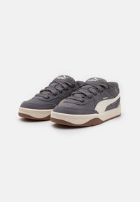 Gray suede sneakers with white accents, featuring a thick rubber sole, textured fabric, and traditional lace-up design.