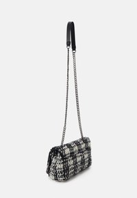 Borsa in tweed bianco e nero, di forma rettangolare con texture trapuntata e tracolla a catena, caratterizzata da accenti in nero a contrasto.