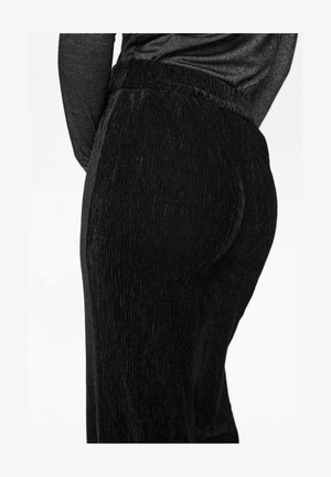 Schwarze Cordhosen mit strukturierter Oberfläche, ausgestattet mit einem elastischen Bund und einer körperbetonten Silhouette, seitlich gezeigt.