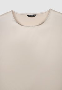 Maglia a girocollo color beige chiaro realizzata in materiale liscio. Presenta un design semplice senza motivi o ornamenti. Etichetta della taglia visibile all'interno.