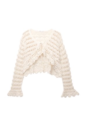 Gilet au crochet en blanc cassé. Il présente un design court, des manches évasées et une fermeture à nouer à l'avant avec un motif de tricot ouvert.