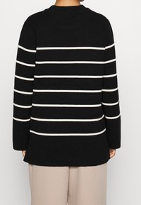 Maglione nero lavorato a maglia con strisce orizzontali bianche, colletto a giro, maniche lunghe e vestibilità rilassata. Texture morbida e lunghezza media.