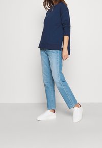 Felpa blu navy con maniche lunghe, caratterizzata da polsini e bordo a costine. Abbinarla a jeans aderenti azzurri e sneakers bianche.