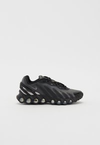 Baskets de sport noires avec une tige texturée, présentant un design épuré, des accents réfléchissants et une semelle épaisse avec des billes de coussinage transparentes.