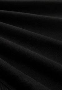 Tessuto nero con una texture morbida e liscia, mostrato in pieghe delicate e ombre, che evidenziano la qualità del materiale e la caduta.