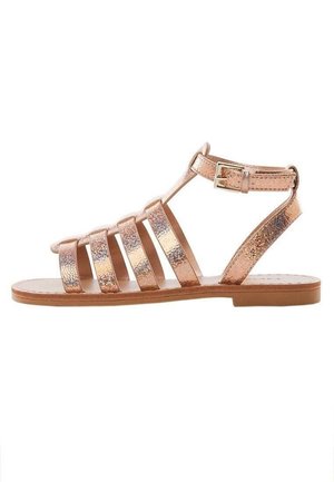 Rosenblød metallic flad sandal med flere forreste remme og en ankelrem med spænde-lukning.