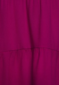 Tejido fucsia con una textura suave y una costura fruncida en la cintura, creando una silueta acampanada. Sin patrones o acentos visibles.