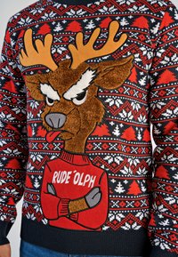 Czerwono-czarny świąteczny sweter z pluszowym, kreskówkowym reniferem z dużymi rogami, ubranym w czerwony sweter z napisem "RUDE 'OLPH" oraz geometrycznymi wzorami.