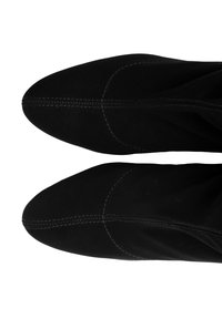 Bottes basses en daim noir avec bouts pointus et détails de coutures discrètes. Texture douce et design ajusté pour une apparence élégante.