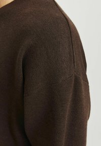 Maglione marrone in maglia con scollatura rotonda, texture liscia, dettagli a costine sottili e maniche a raglan per una vestibilità rilassata.