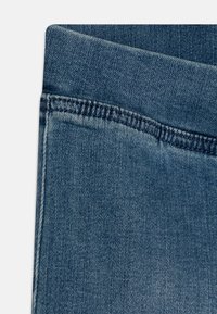 Temno modra denim tkanina z rahlo teksturo, ki ima raven pas in čiste šive ob robovih. Brez vidnih okraskov.