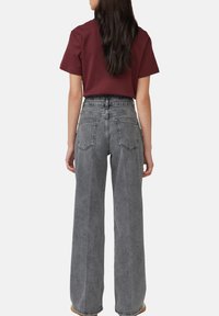 Grijze wijde spijkerbroek met hogere taille, voor- en achterzakken, en een ontspannen pasvorm. Gekocht met een maroon T-shirt met korte mouwen.