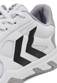 Weißer Sportschuh aus Mesh- und synthetischen Materialien. Verfügt über ein schwarzes Zickzackdesign, graue Akzente und weiße Schnürsenkel. Die Textur ist glatt und atmungsaktiv.