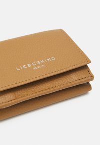 Taschenledergeldbörse aus hellbraunem Leder mit strukturierter Oberfläche, im Faltendesign und geprägt mit dem silbernen Logo "LIEBESKIND BERLIN".