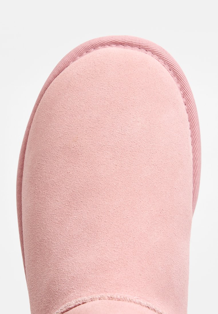 Rosa Wildlederstiefel mit runder Zehenkappe, strukturierten Oberflächen und einer gesteppten Akzentnähte entlang der Sohle. Glatte Innenauskleidung sichtbar an der Öffnung.