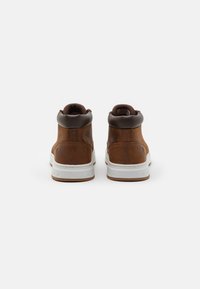 Bruna läder högsålda sneakers har en vadderad brun krage, vit gummisula och subtil logotypdetalj på hälen.