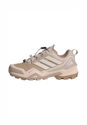 Lichtbeige outdoorschoen met een ademende bovenkant van mesh, een geometrisch patroon, versterkte neus en een rubberen zool met diepe profielen voor grip.