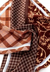 Écharpe en soie présentant un mélange de couleurs marron et orange, avec des motifs à carreaux et floraux, texture lisse et une bordure d'accent blanc.