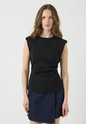 Zwarte mouwloze top met een ronde halslijn, vervaardigd uit zachte stof en met een geplooide detail bij de taille. Gecombineerd met een spijkerrok.