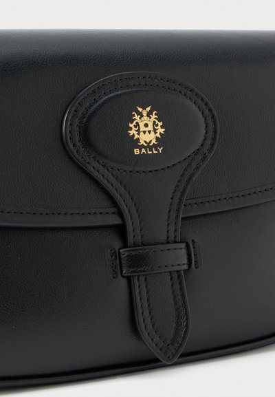 Black leather bag featuring a rounded flap, stitched accents, and a gold Bally logo. Includes a strap with a buckle closure detail.