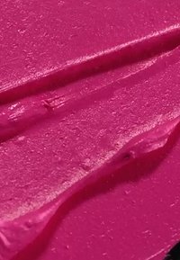 Prodotto cremoso di un brillante colore rosa, con una consistenza liscia, caratterizzato da sottili accenti lucidi e leggere scanalature sollevate dovute all'applicazione.