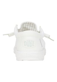 Weiße Canvas-Slipper mit strukturiertem Fabric, ausgestattet mit einem "HEY DUDE"-Logo, einer gesprenkelten Sohle und einem elastischen Fersenriegel für einfaches An- und Ausziehen.
