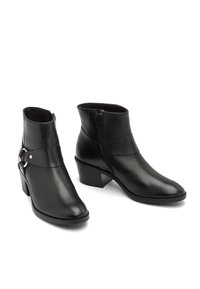 Une paire de bottines noires en cuir avec des talons carrés, une fermeture éclair sur le côté et une sangle décorative avec un anneau en métal sur fond blanc.