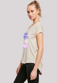 Beige short-sleeve t-shirt with a round neckline, featuring a graphic design in blue and purple. Hem is slightly longer at the back.