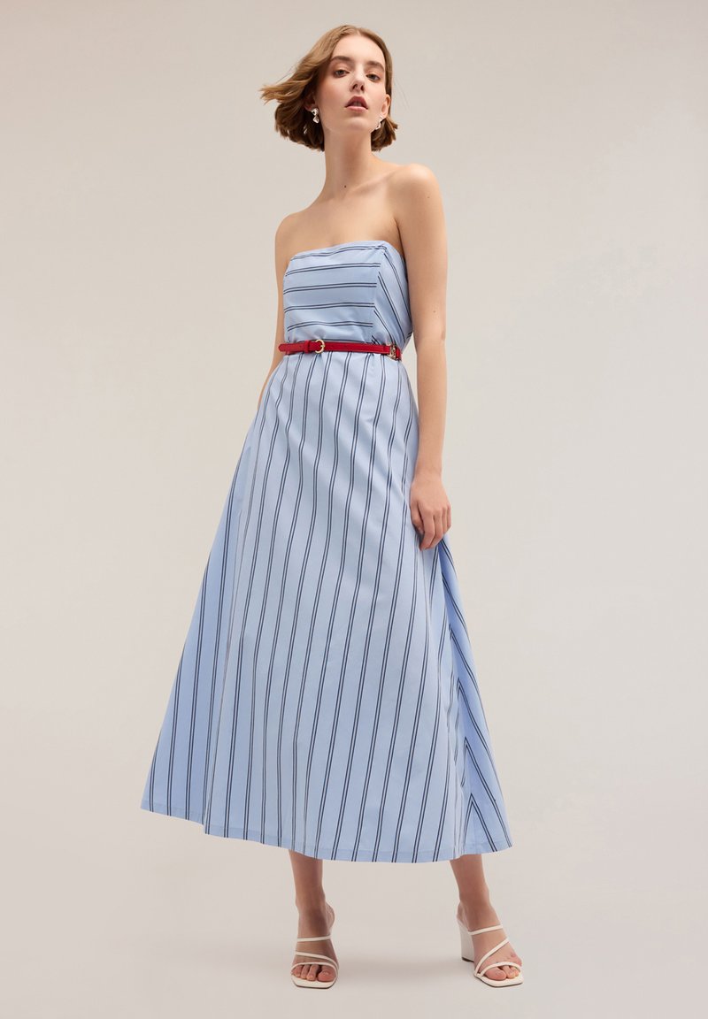 Vestido maxi sin tirantes en tejido azul claro con rayas verticales en azul marino, acentuado con un cinturón rojo; textura suave y silueta fluida.