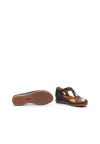 Sandales compensées en cuir noir avec des accents marron. Elles présentent une ouverture sur le devant, des découpes, des détails brodés et une semelle en caoutchouc texturé.