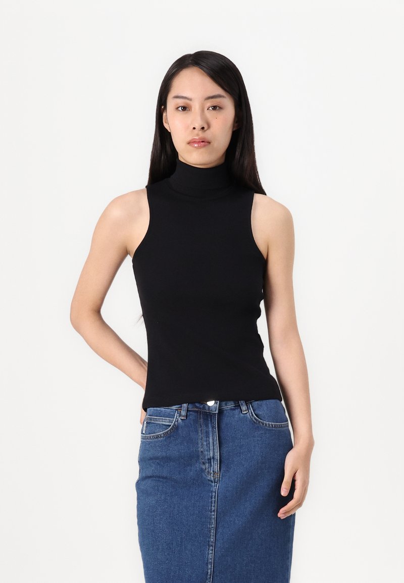 Top nero senza maniche con design aderente, abbinato a una gonna a matita in denim blu con tasche frontali e taglio a mezza lunghezza.