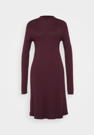 Vestido de malha canelada em burdeos profundo, com mangas longas e gola alta. Forma A em corte evasé, textura suave, caindo acima dos joelhos.