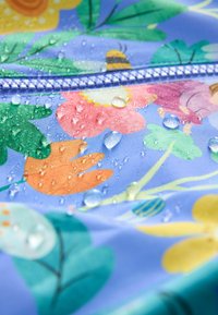 Voděodolná látka s květinovým vzorem v odstínech modré, oranžové, růžové a zelené. Na povrchu jsou kapky vody.